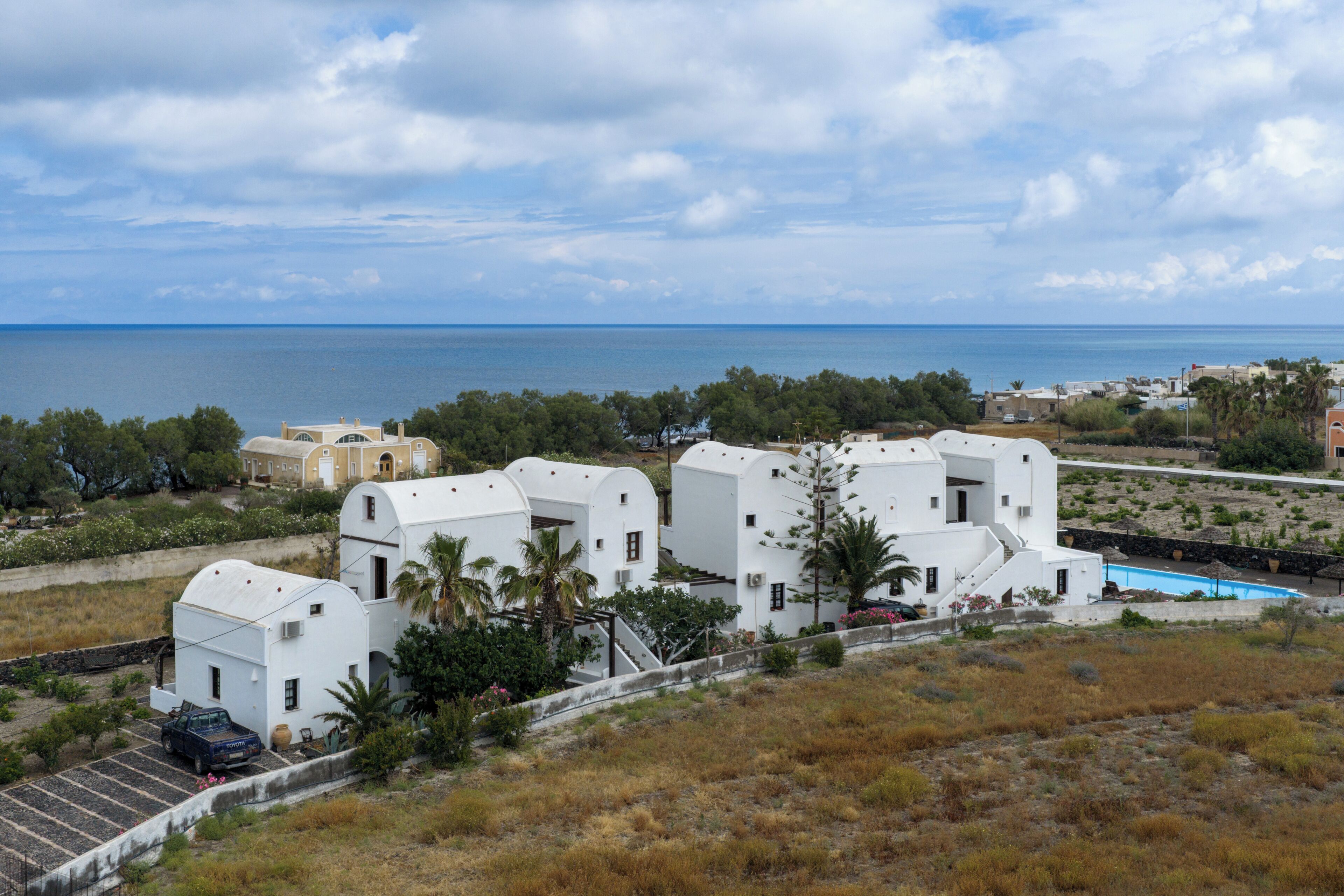 Una propietat costanera amb edificis blancs, una piscina i vista al mar.