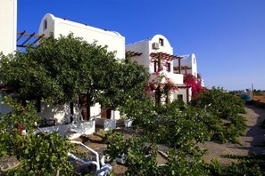 Un edificio blanco con jardín delantero, rodeado de árboles y arbustos.