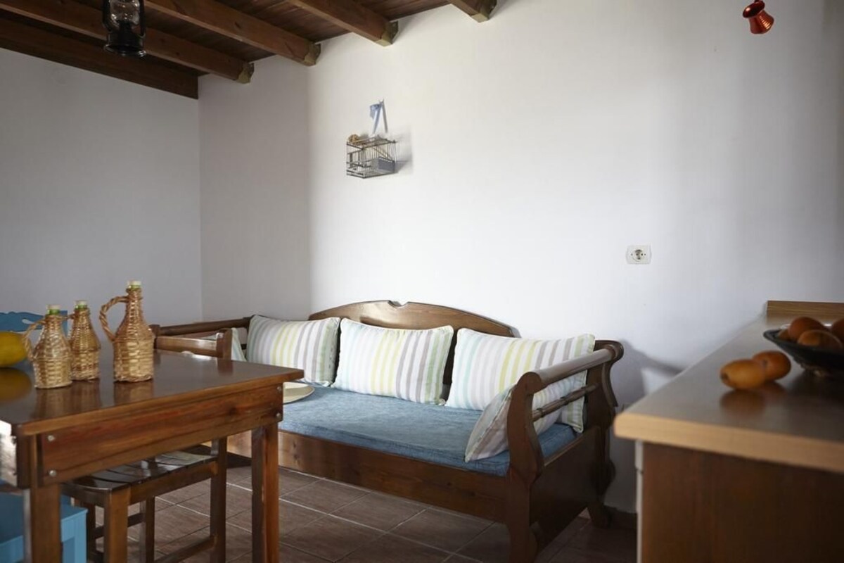 A room with a wooden bed, a wooden table, and a small wall-mounted shelf.