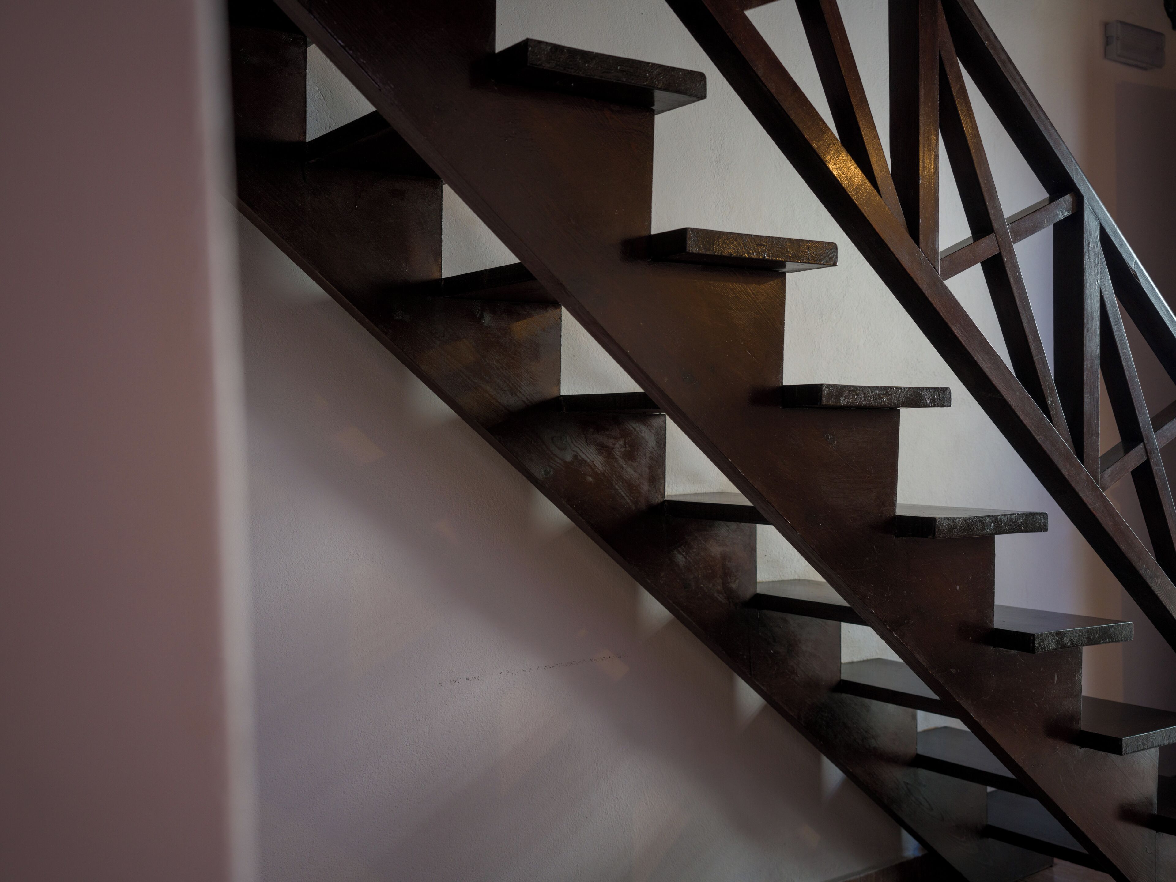 A wooden staircase with a geometric design, leading to an upper floor.