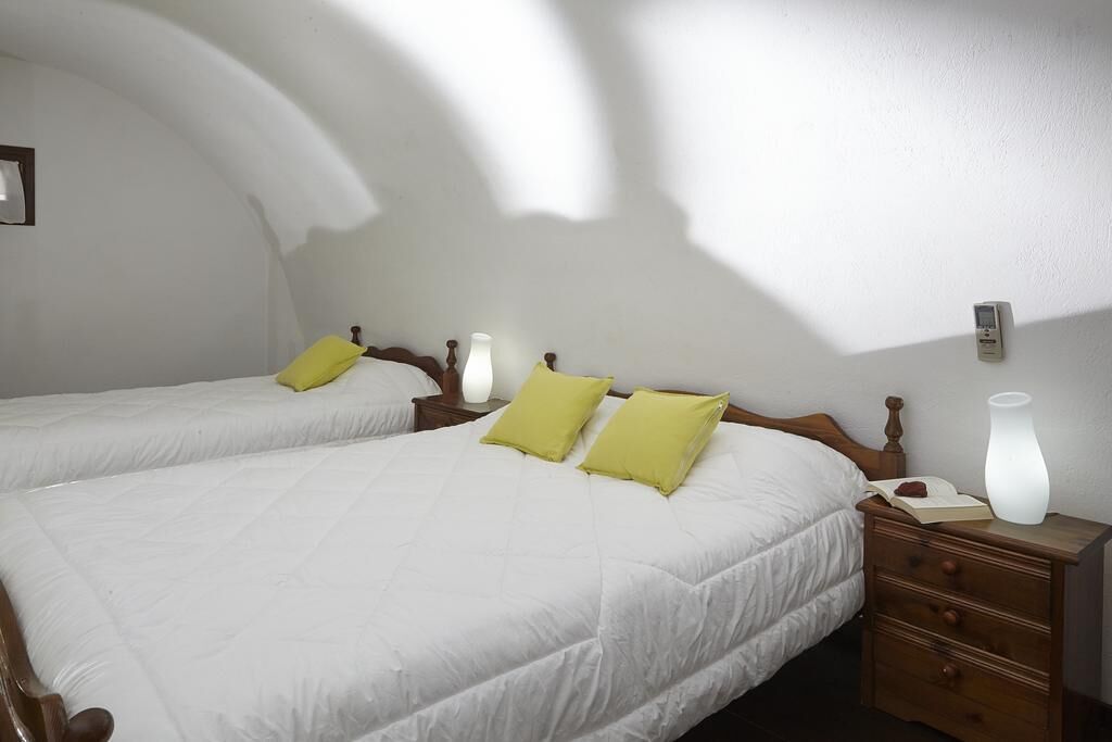 A hotel room with two beds, a nightstand, a bedside lamp, and a wall-mounted thermostat.