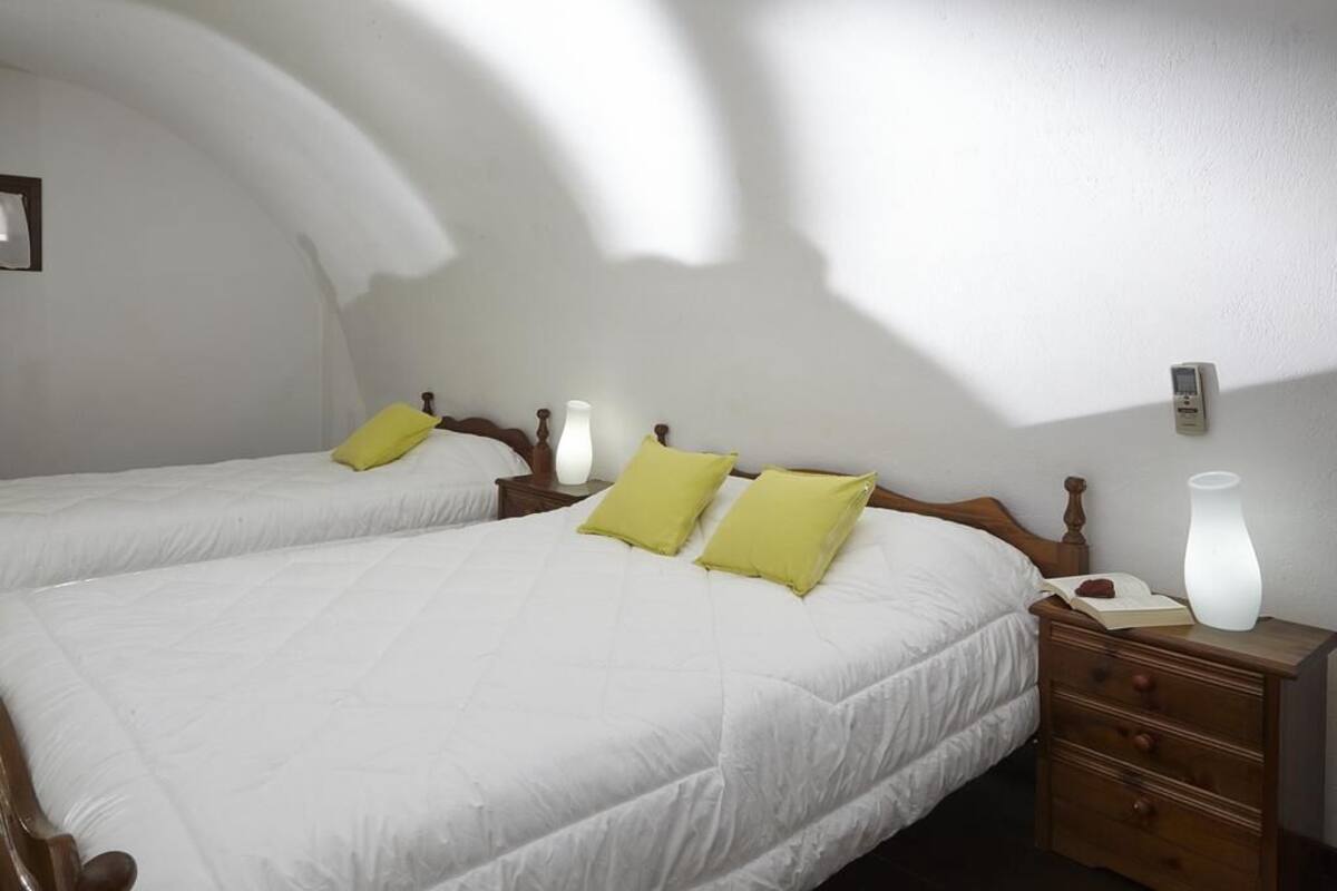 A hotel room with two beds, a nightstand, a bedside lamp, and a wall-mounted thermostat.