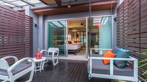 An outdoor patio with a swing seat, white chairs, and a table. - Red Ginger Chic Resort (Krabi)