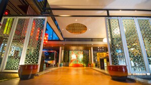 A modern hotel lobby with a wooden floor, a large circular light fixture, and decorative glass panels. - Red Ginger Chic Resort (Krabi)