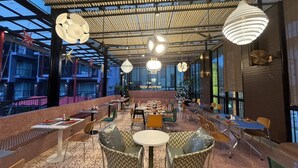 A restaurant with a covered outdoor seating area, tables, chairs, and hanging light fixtures. - Red Ginger Chic Resort (Krabi)