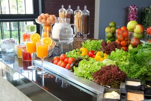 Un bufé con diversas frutas, verduras y bebidas.