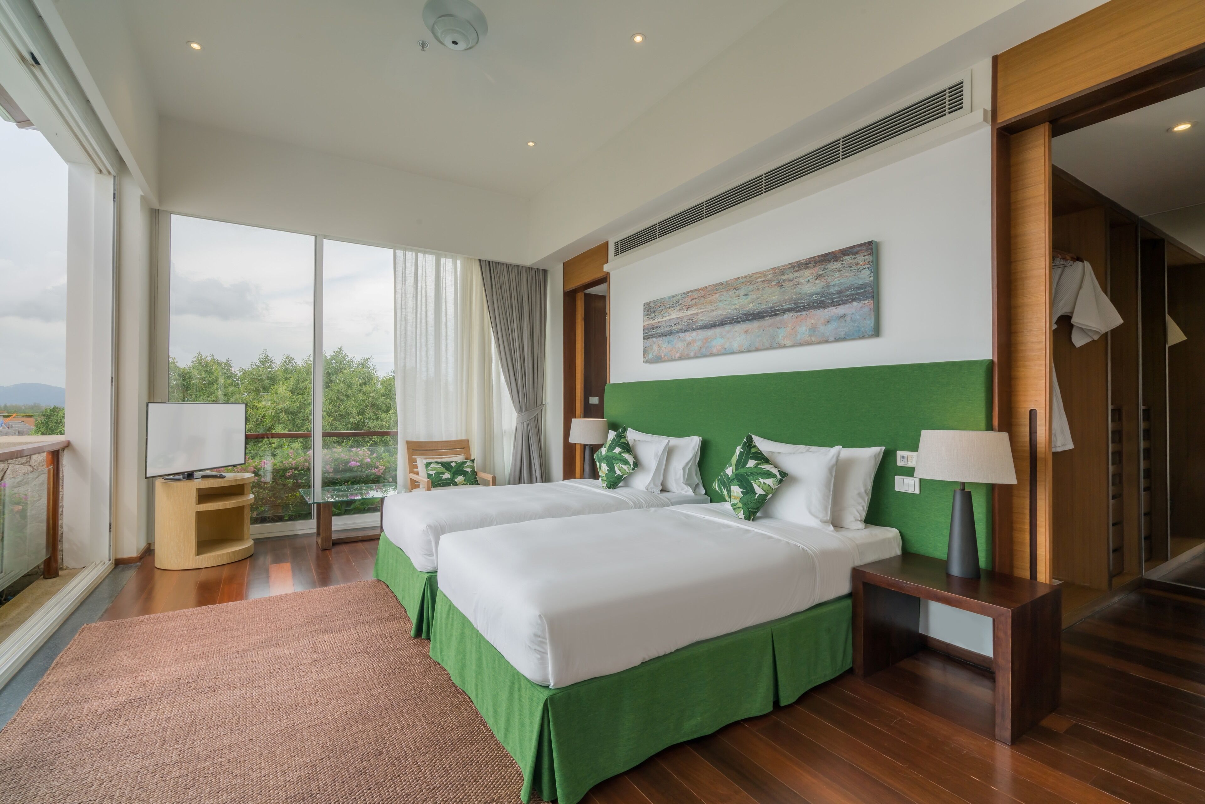 Une chambre d’hôtel avec deux lits, une grande fenêtre, un tableau et une vue sur la verdure.