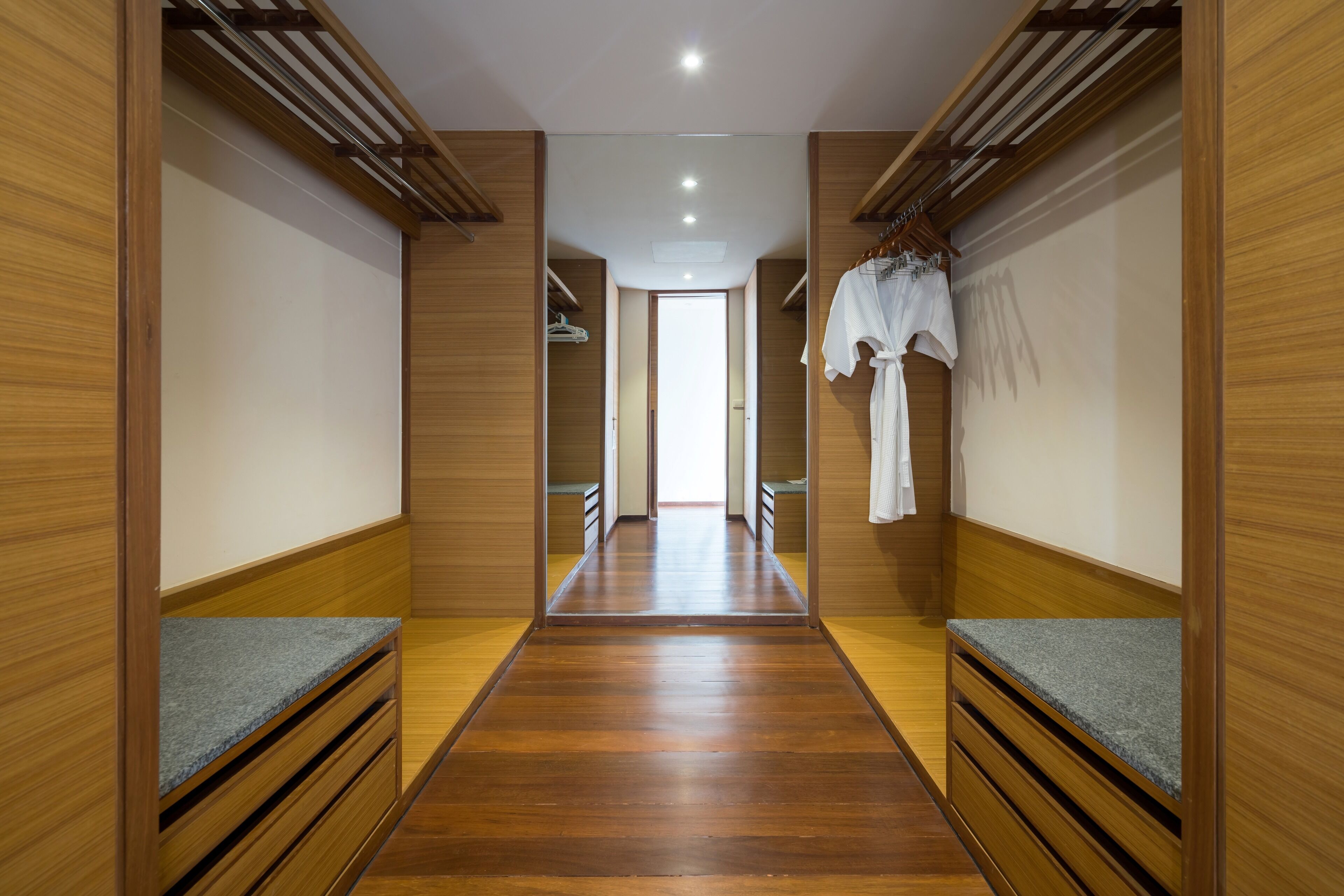 Un pasillo con paredes y piso de madera que conduce a una habitación luminosa.
