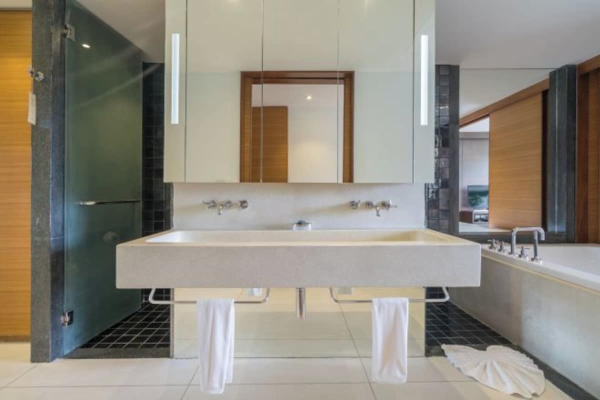 Un baño moderno con un lavamanos grande, un espejo y una bañera.