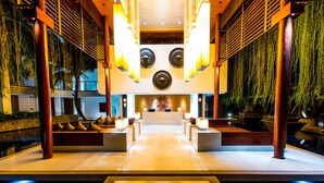 A modern lobby with a reception desk, seating areas, and a water feature.