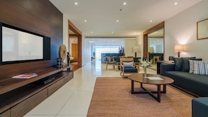 A modern living room with a flat-screen TV, dark wood furniture, a coffee table, and a sofa with striped cushions.