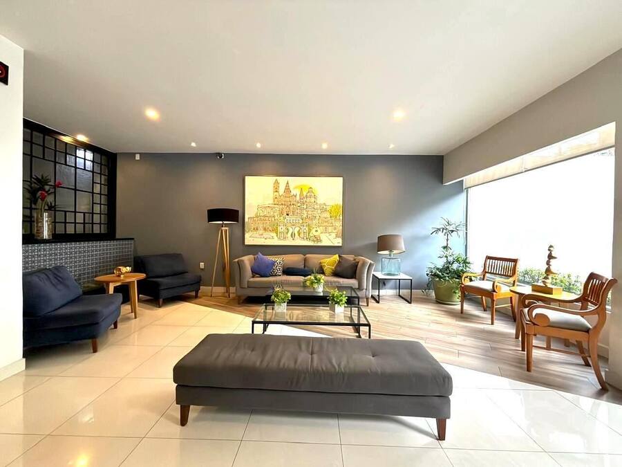 Una sala de estar moderna con un sofá, un sillón, una mesa de centro y un cuadro en la pared.