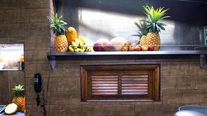 A kitchen counter with a variety of fruits and a wall-mounted phone. - Hotel Arboledas Expo (Guadalajara)