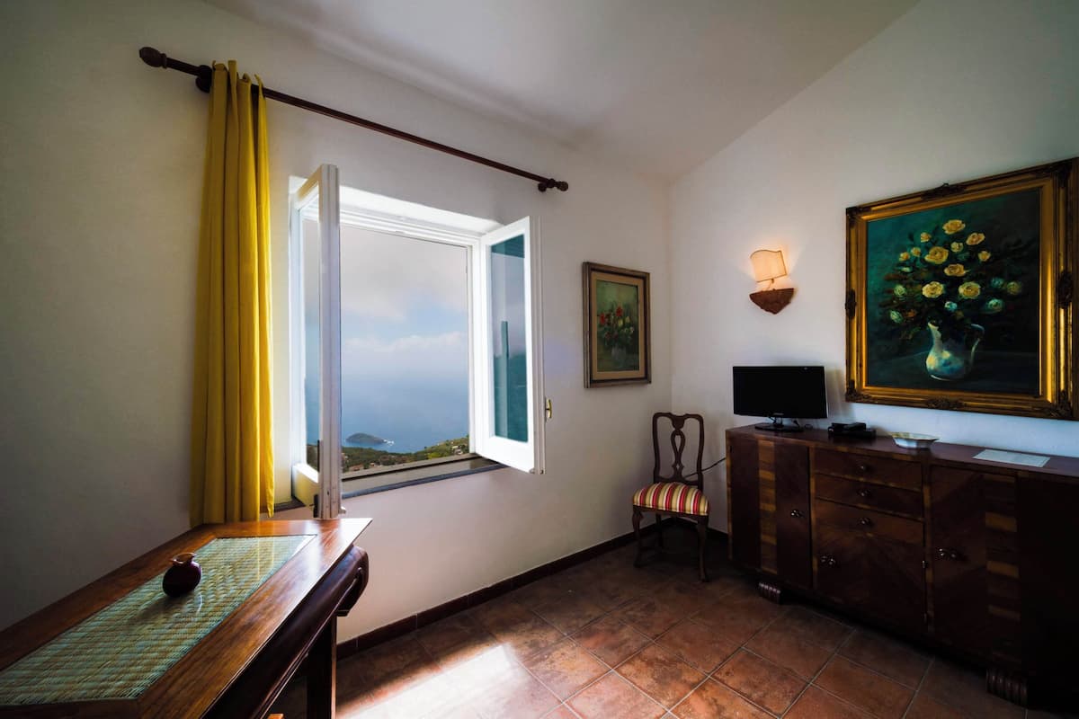 Ein Zimmer mit großem Fenster, einem Sessel, einem Fernseher und einem Schrank.