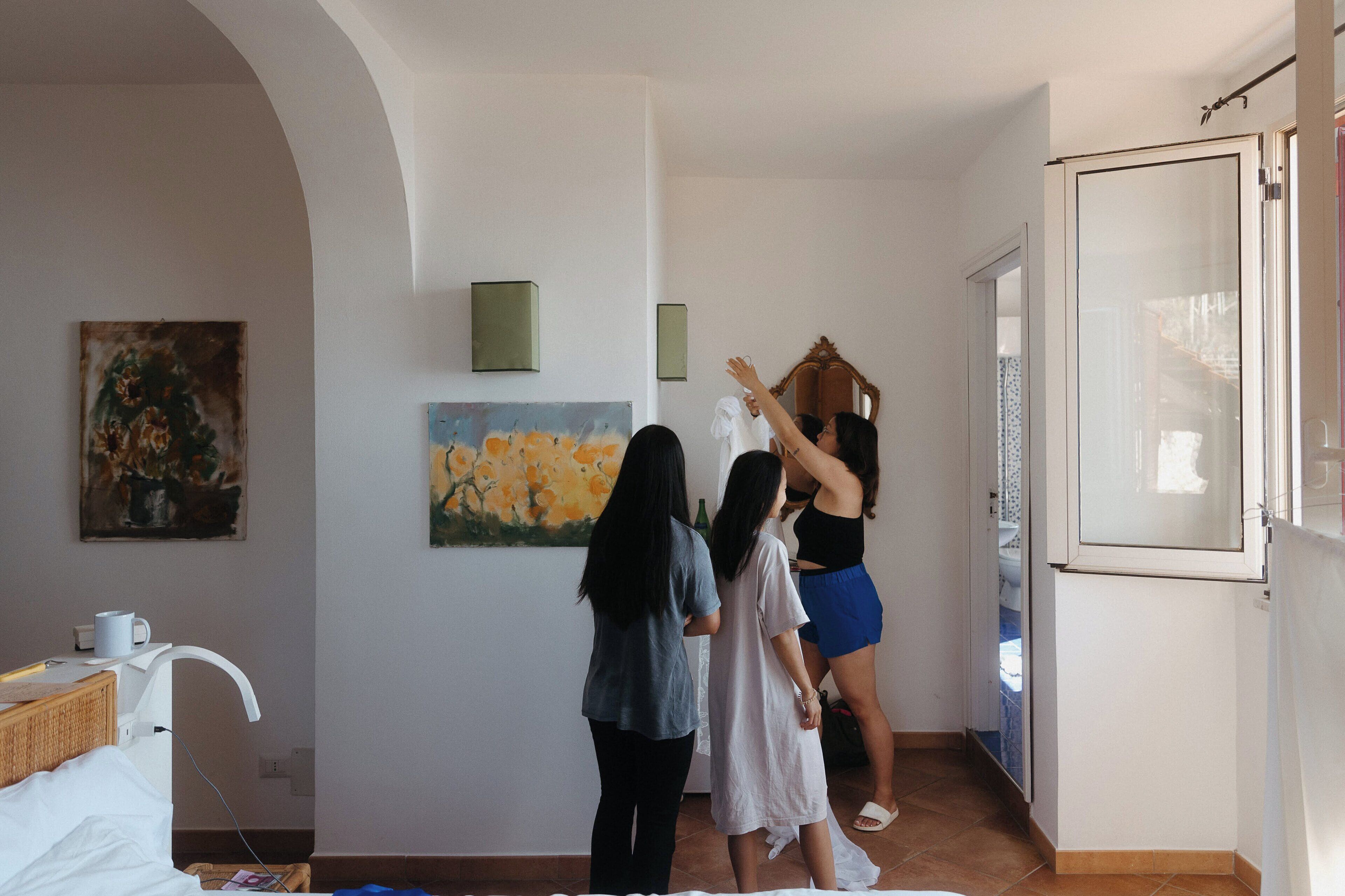 A room with a bed, a painting, a mirror, and a door.