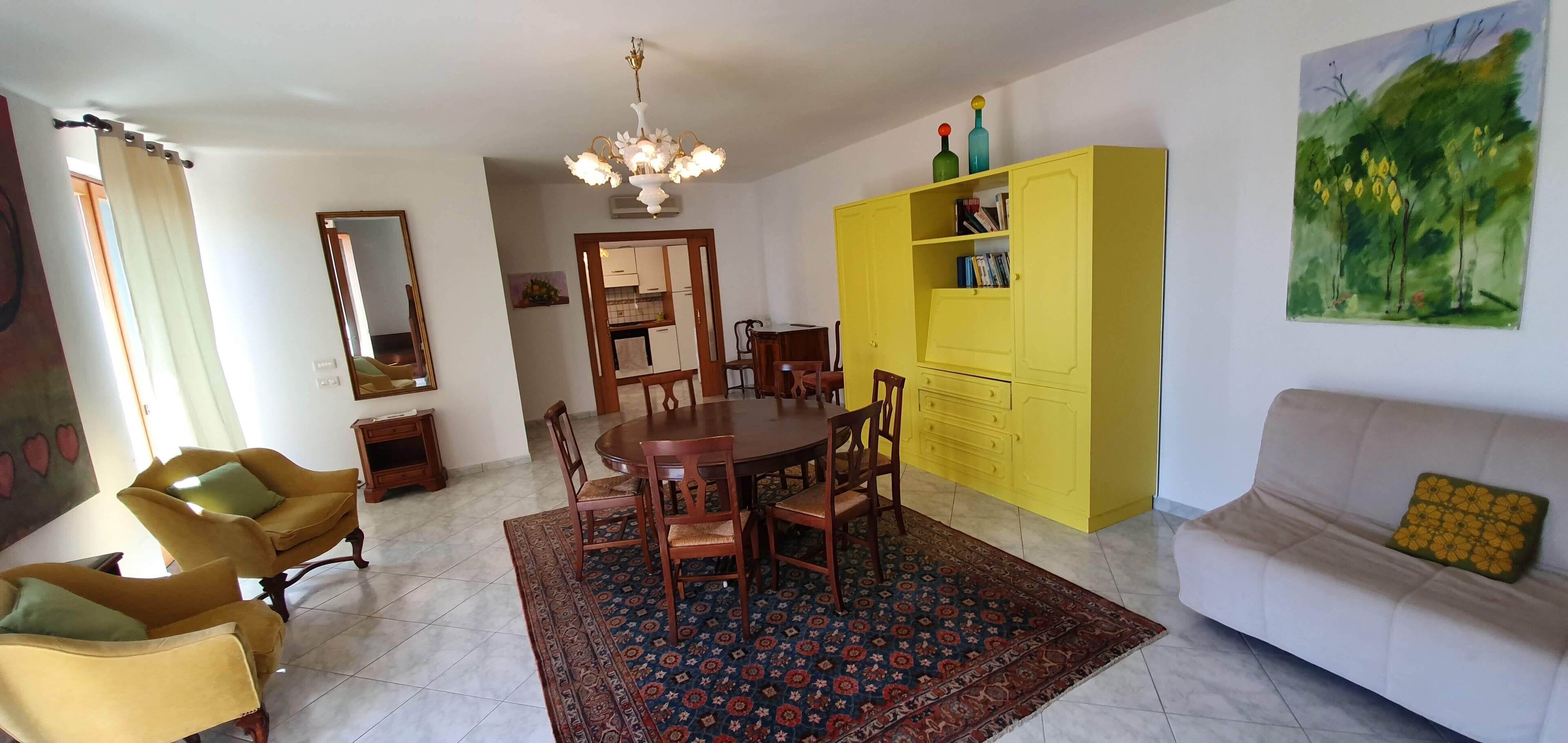 A dining area with a round table, chairs, and a patterned rug.