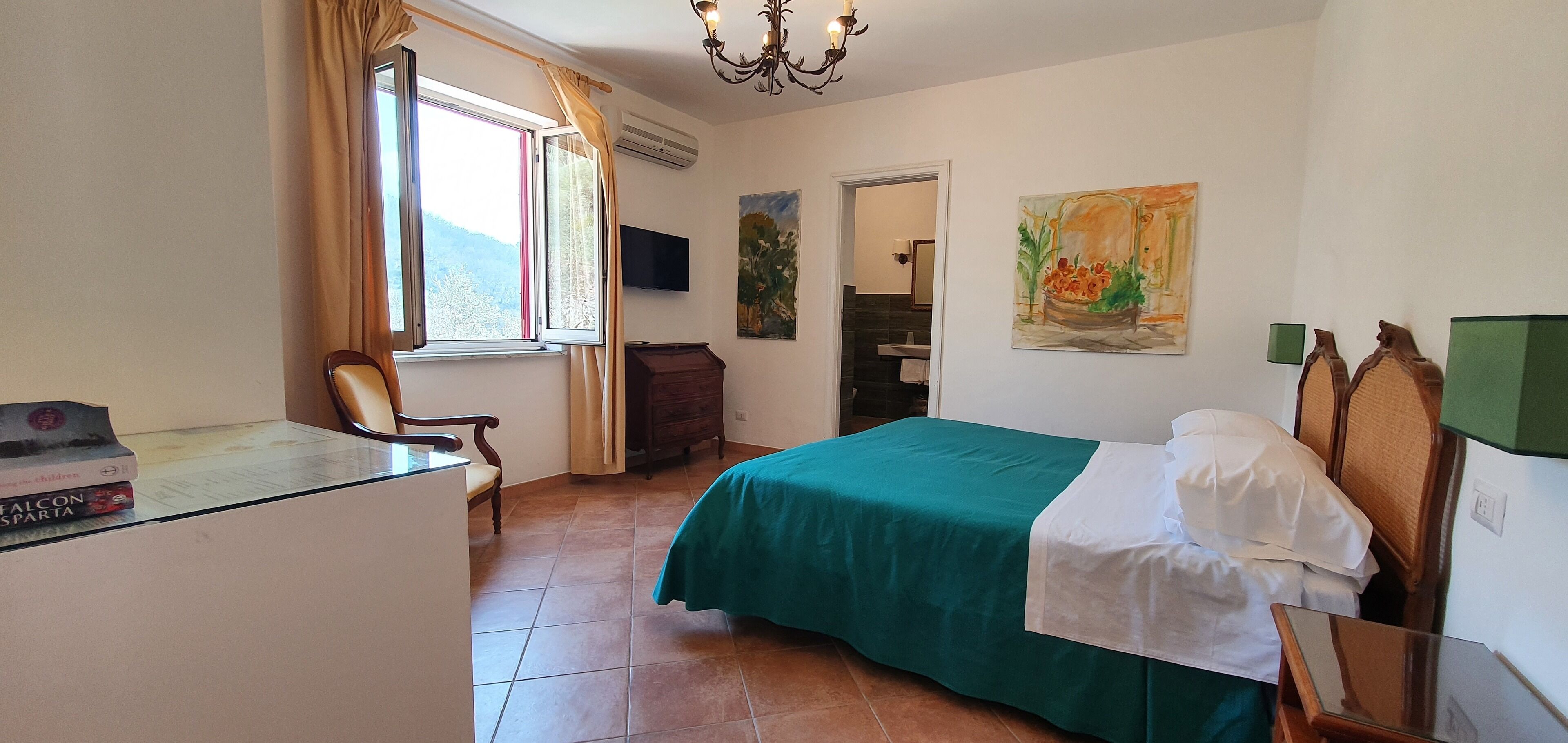 Une chambre d’hôtel avec un lit, un bureau, une chaise, une télévision et un tableau au mur.