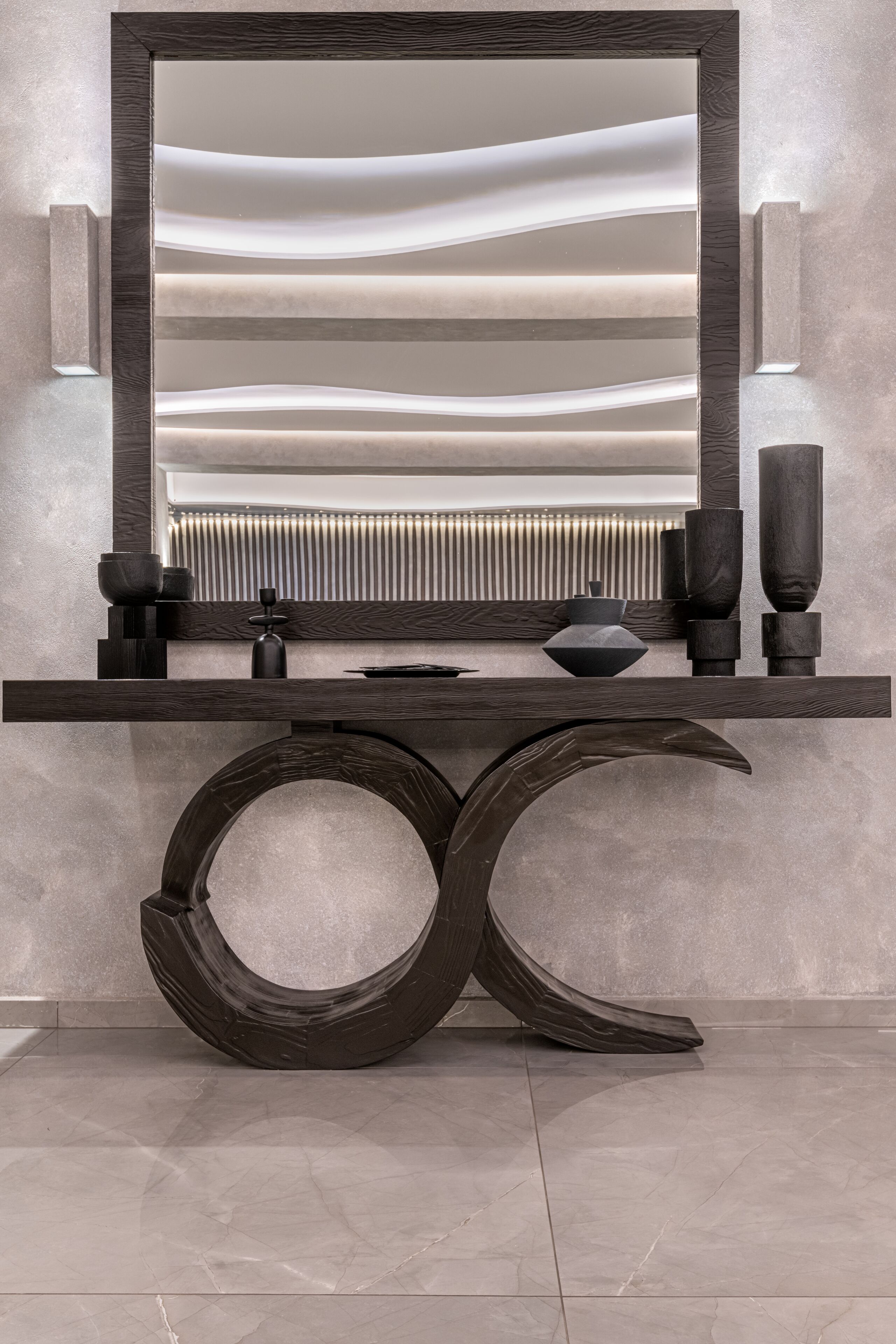 A modern bathroom vanity with a large mirror, a dark wooden console table, and a unique circular base.