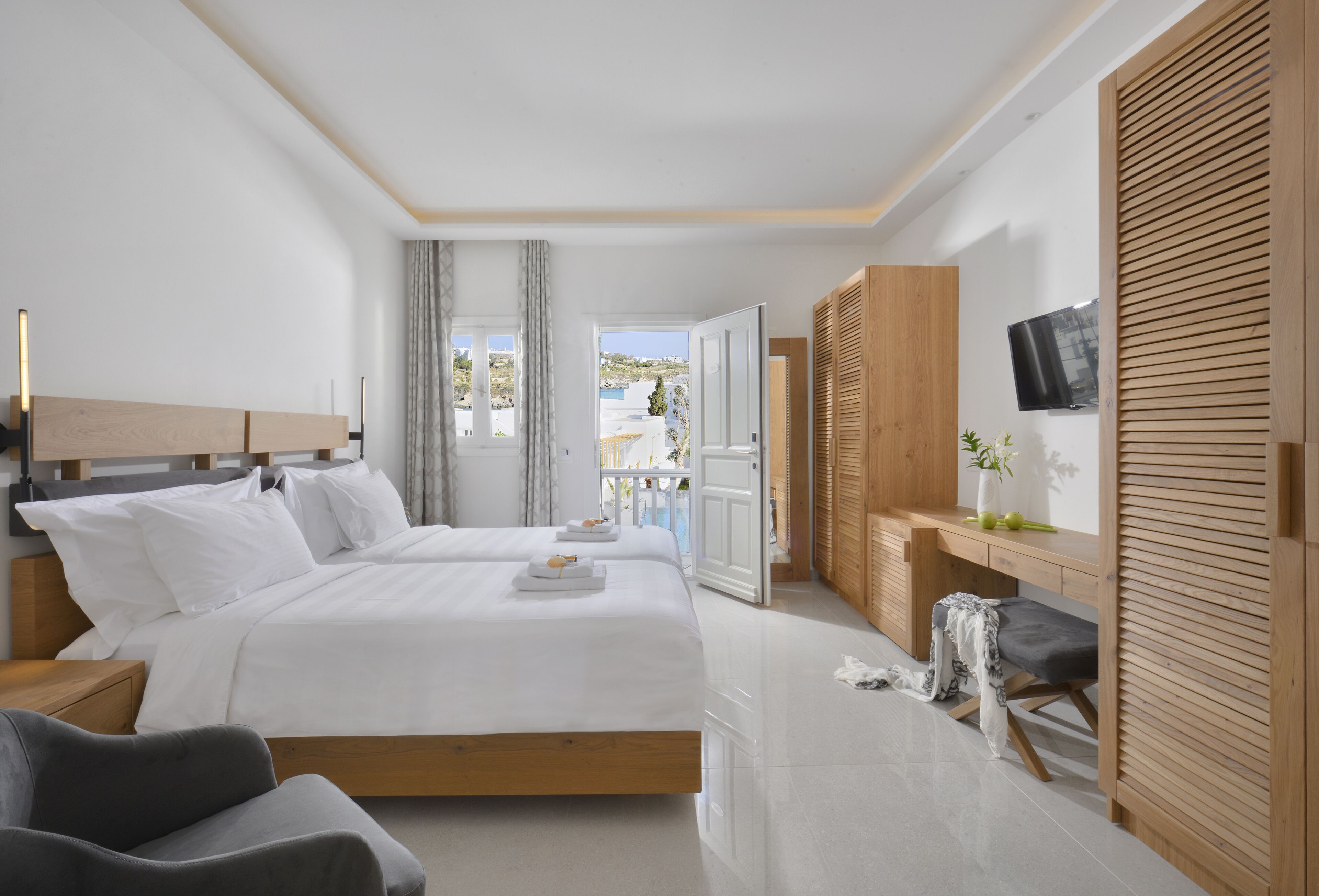 A modern bedroom with a large bed, bedside tables, a desk, and a TV.