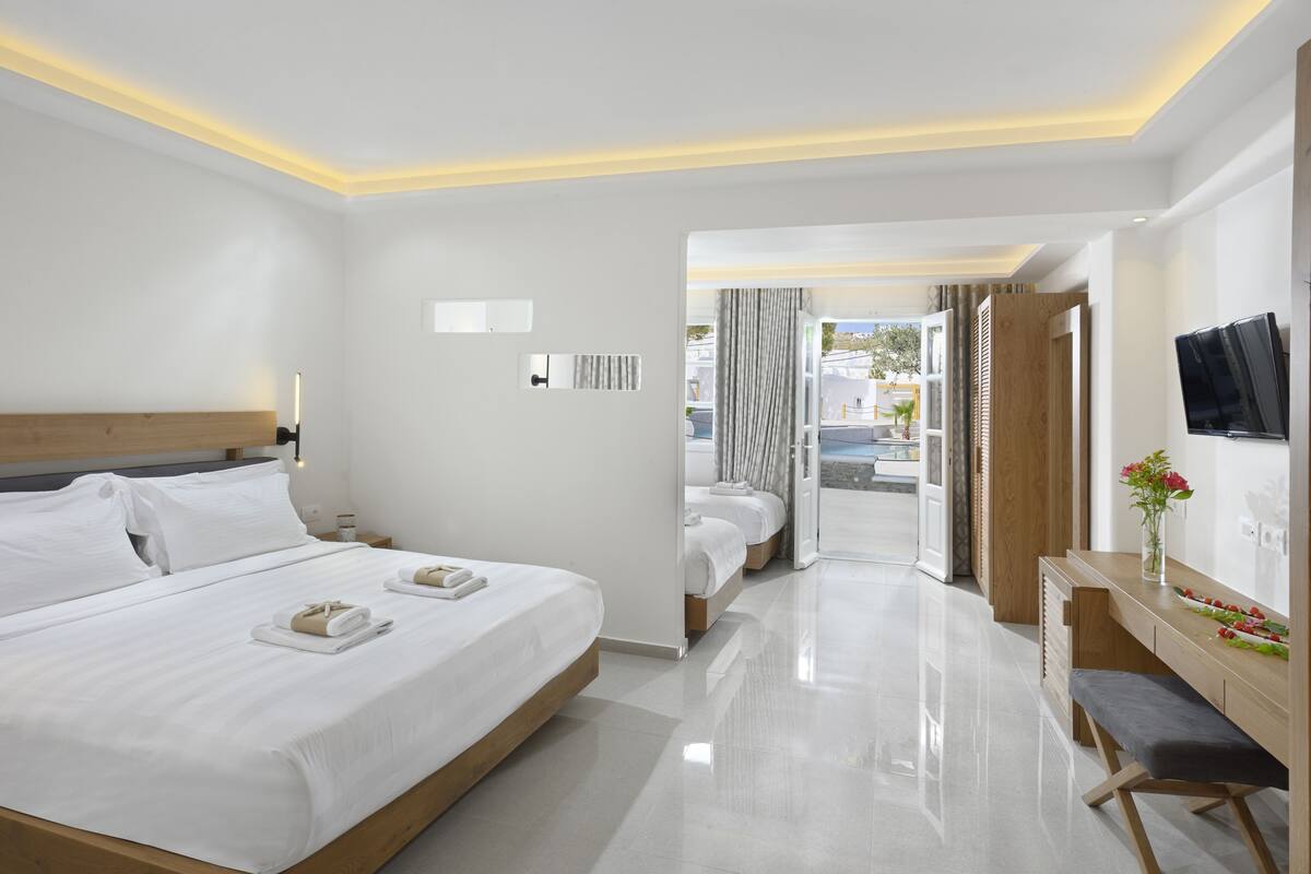 A modern hotel room with a large bed, a desk with a chair, and a TV on the wall.