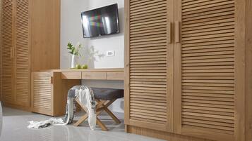 Una habitación moderna con armarios de madera, un televisor de pantalla plana y un escritorio con un florero y planta.