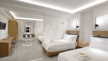 Habitación de hotel moderna con dos camas, un tocador con espejo, un escritorio y un baño visible a través de una puerta abierta.