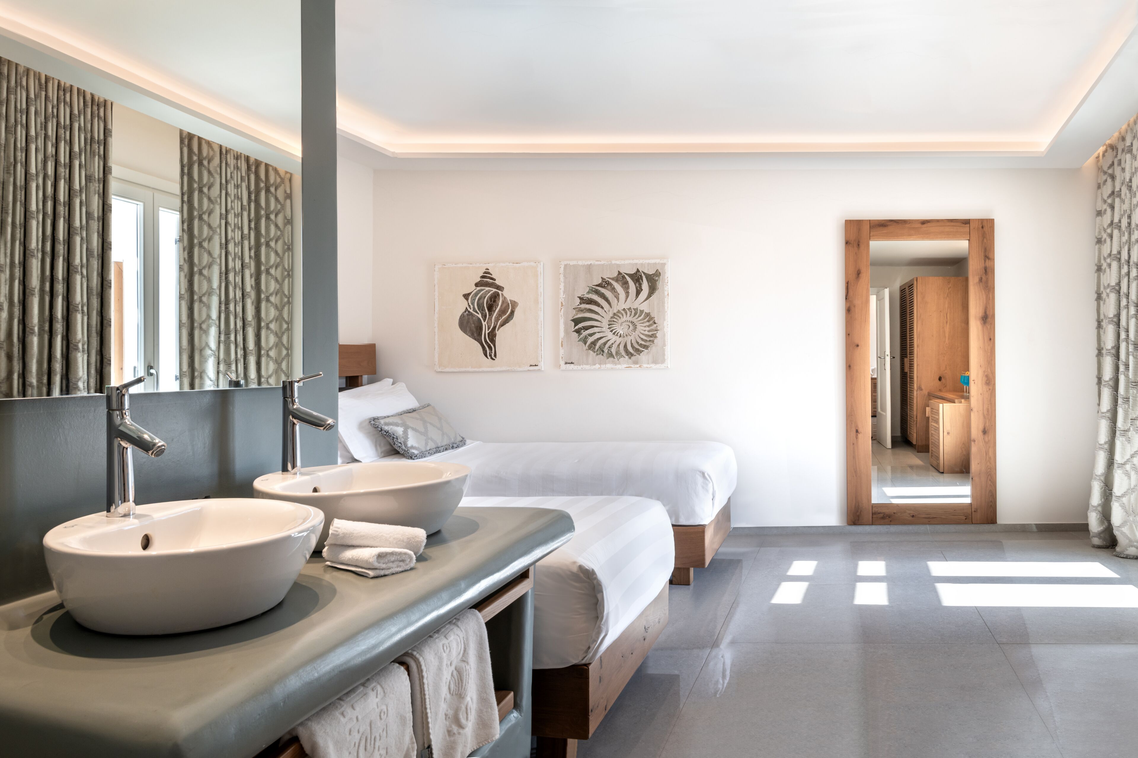 Une salle de bain moderne avec deux lavabos, un miroir et des œuvres d’art accrochées au mur.