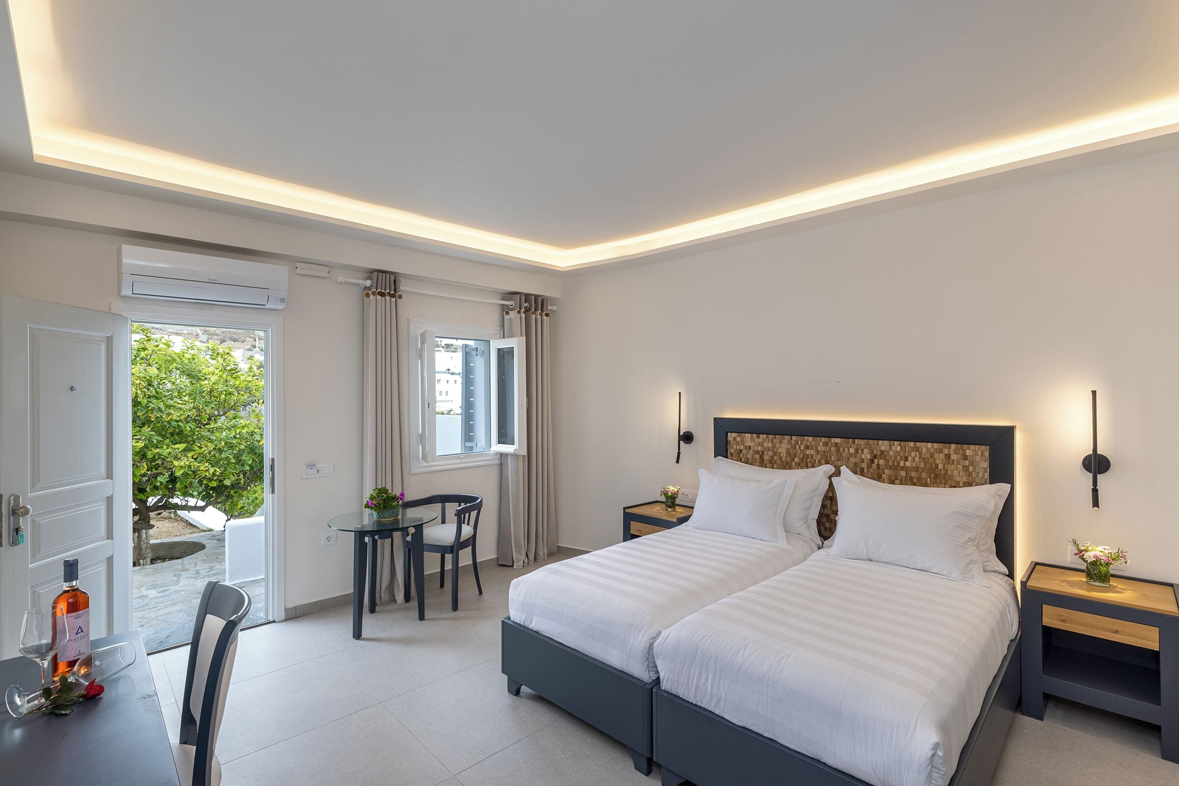 A modern bedroom with a large bed, bedside tables, a desk, and a chair.