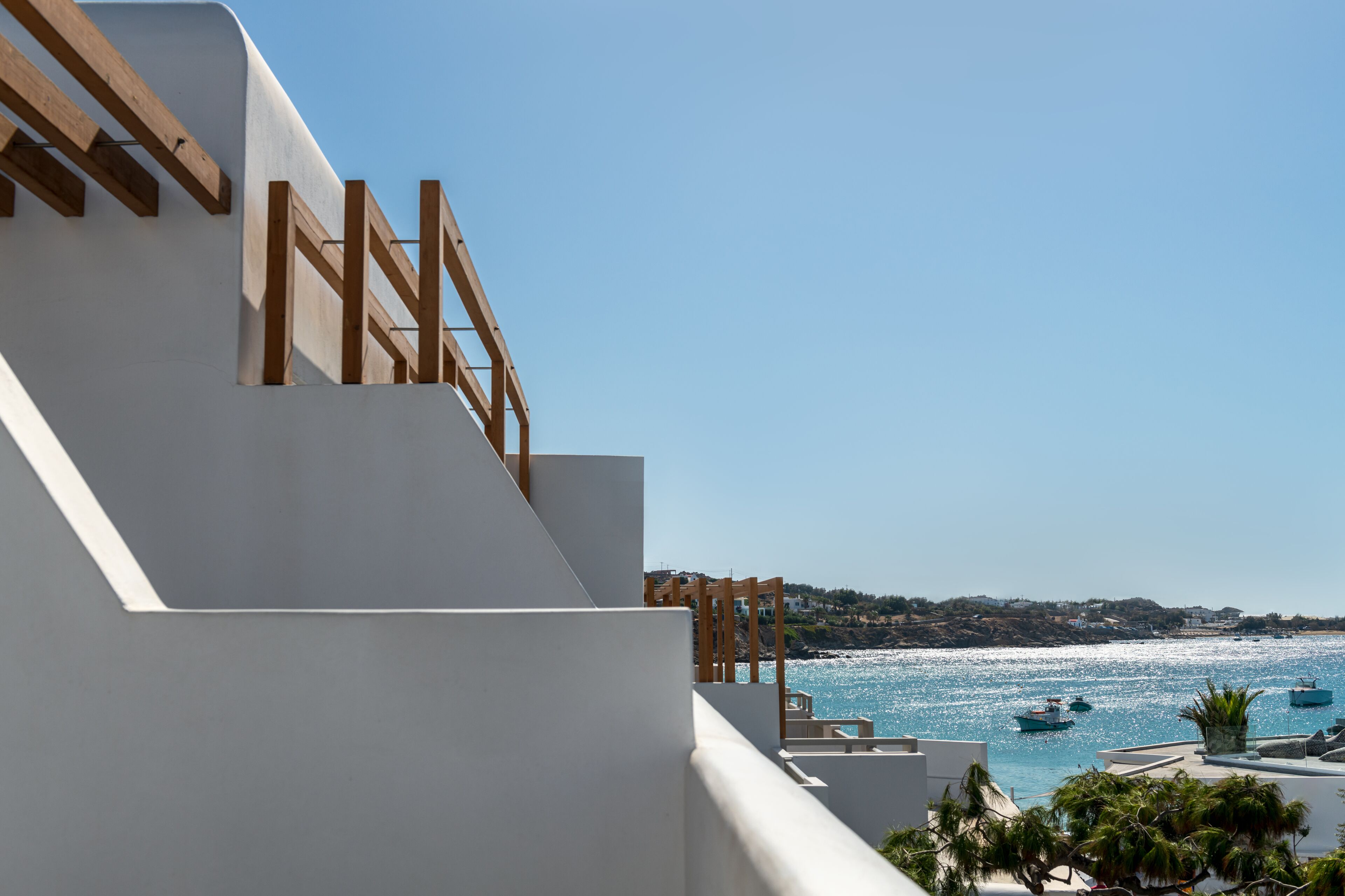 Un bâtiment situé sur la côte, doté d’un balcon donnant sur la mer, de balustrades en bois et offrant une vue dégagée sur les bateaux.