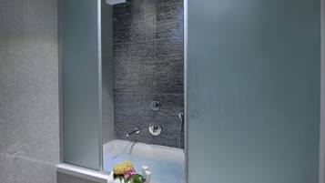 A modern bathroom with a glass-enclosed shower, a white toilet, and a towel rack with a floral arrangement.