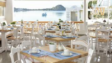 Ein Restaurant mit weißen Stühlen und Tischen, Blick aufs Wasser und einer Speisekarte.