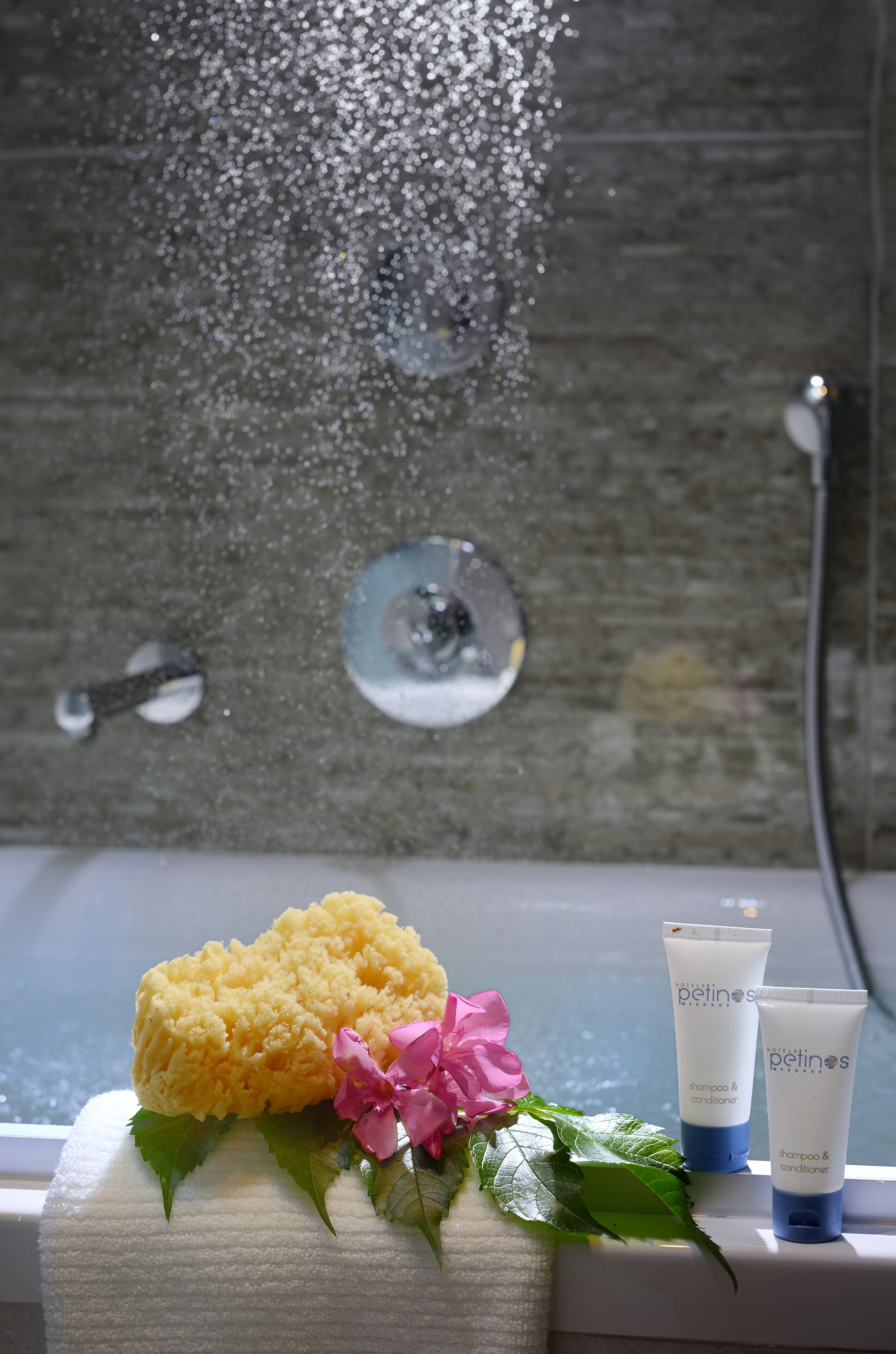 A bathroom with a bathtub, a showerhead, and toiletries on a towel.