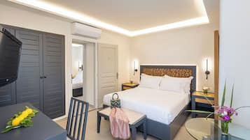 A modern hotel room with a bed, bedside table, chair, and a desk with a chair.