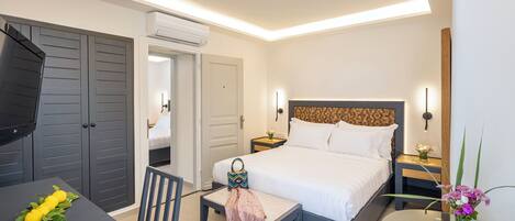 A modern hotel room with a bed, bedside table, chair, and a desk with a chair.