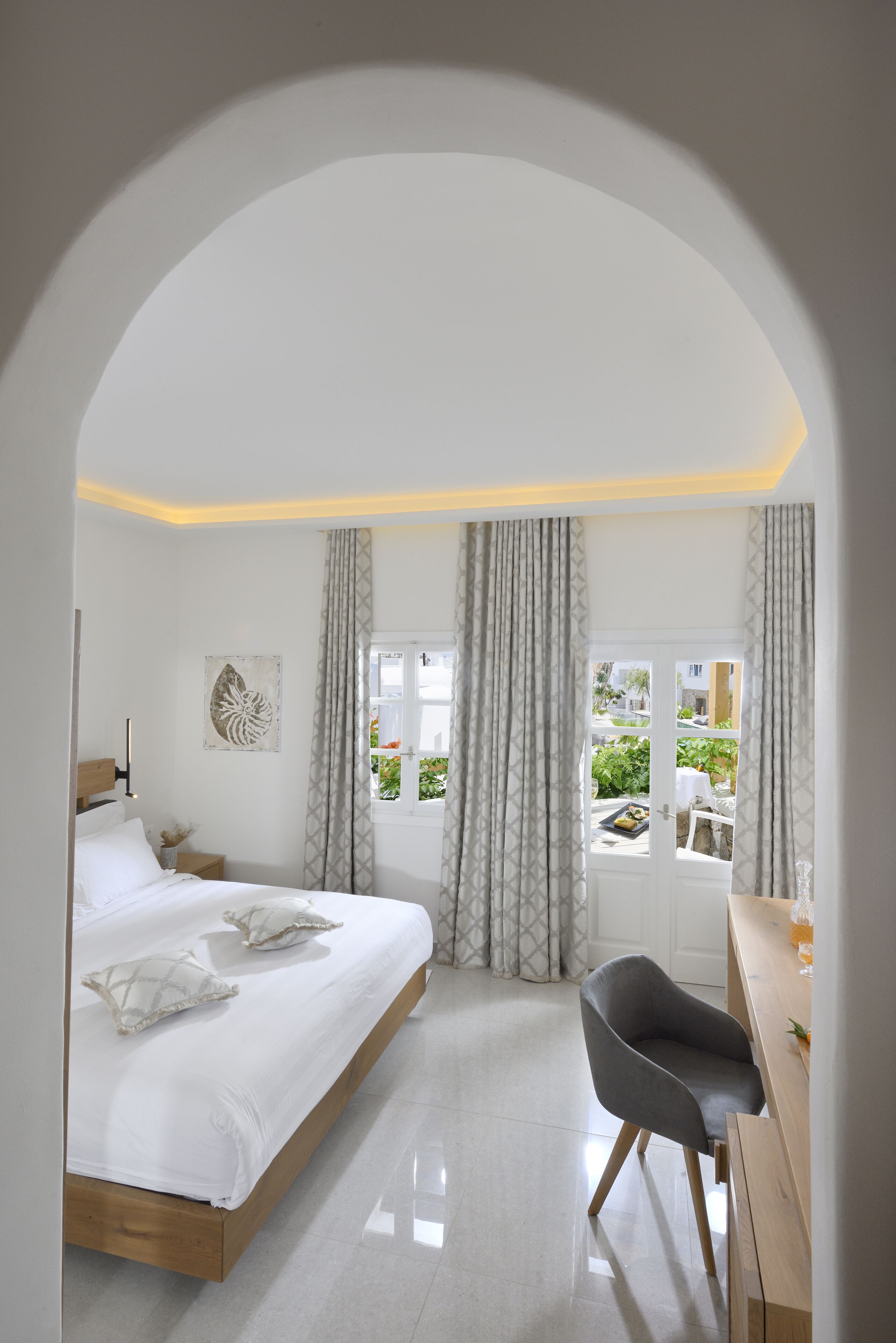 Ein modernes Schlafzimmer mit Bett, Schreibtisch und Stuhl. Ein Fenster mit Vorhängen bietet einen Blick ins Freie.