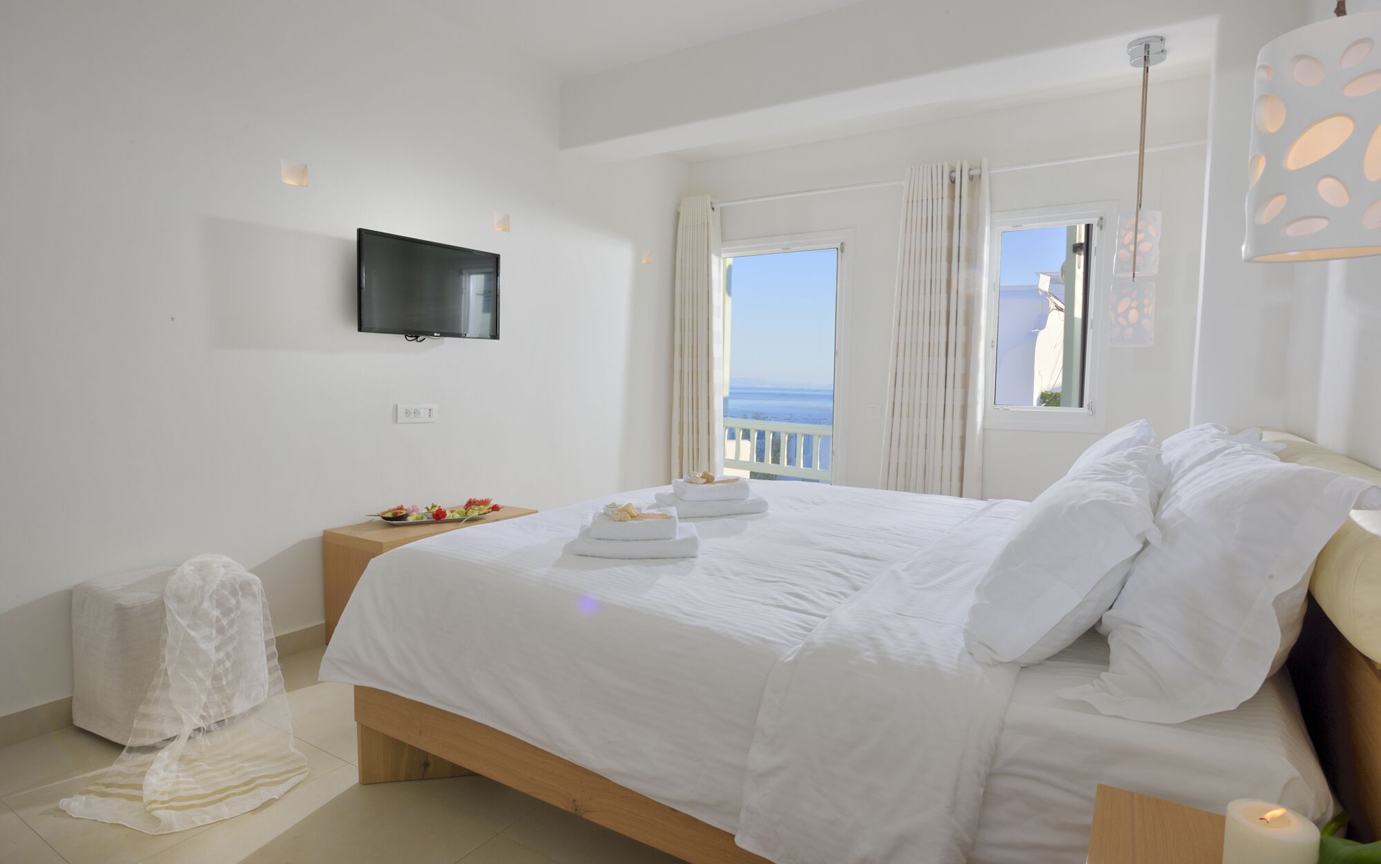 Una habitación de hotel moderna con una cama grande, un televisor de pantalla plana en la pared y un balcón con vistas.