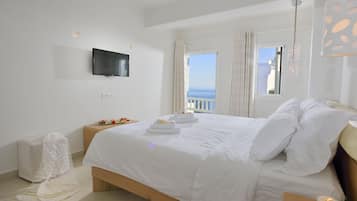 Una habitación de hotel moderna con una cama grande, un televisor de pantalla plana en la pared y un balcón con vistas.