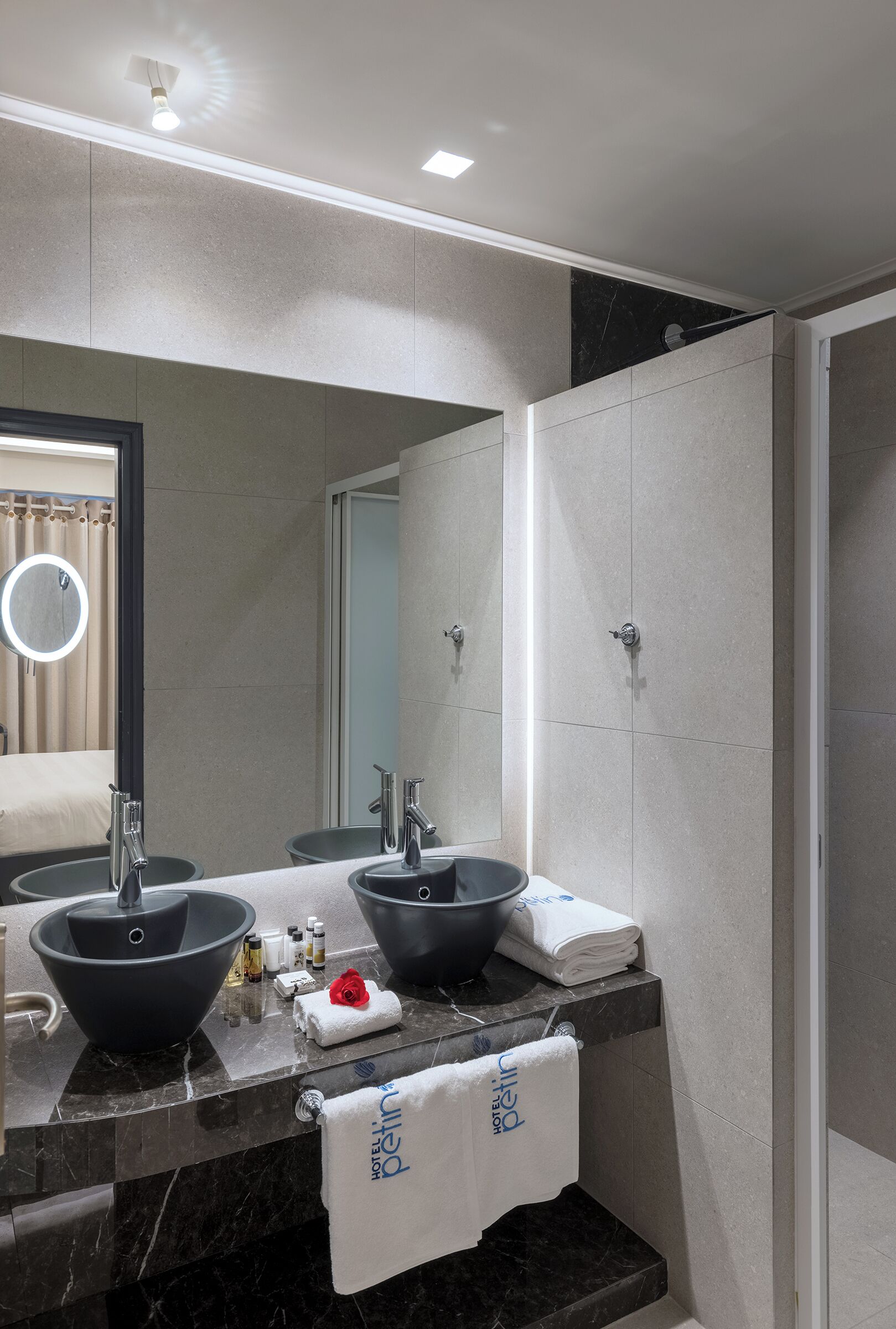 A modern bathroom with two sinks, a large mirror, and a shower area.