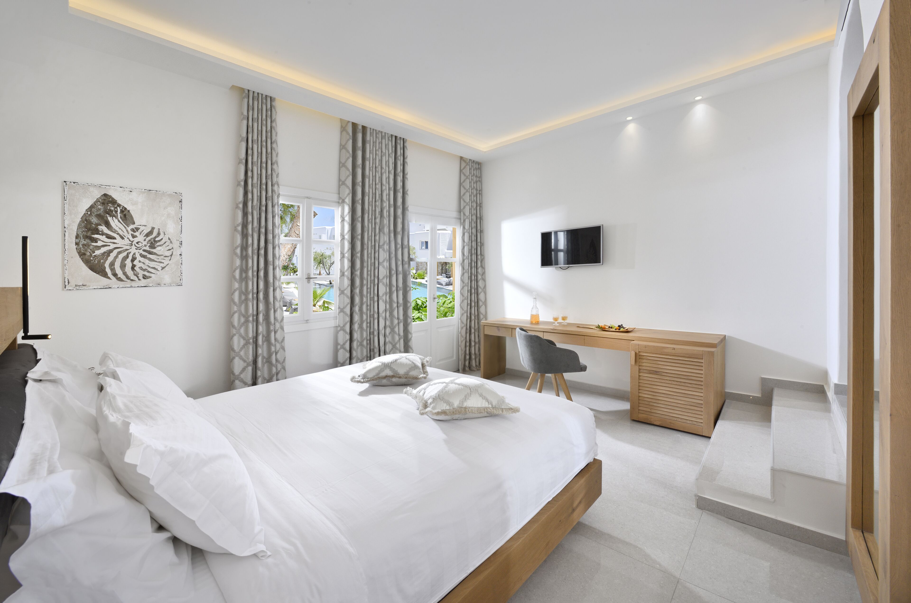 Un dormitorio moderno con una cama grande, un escritorio y un televisor.