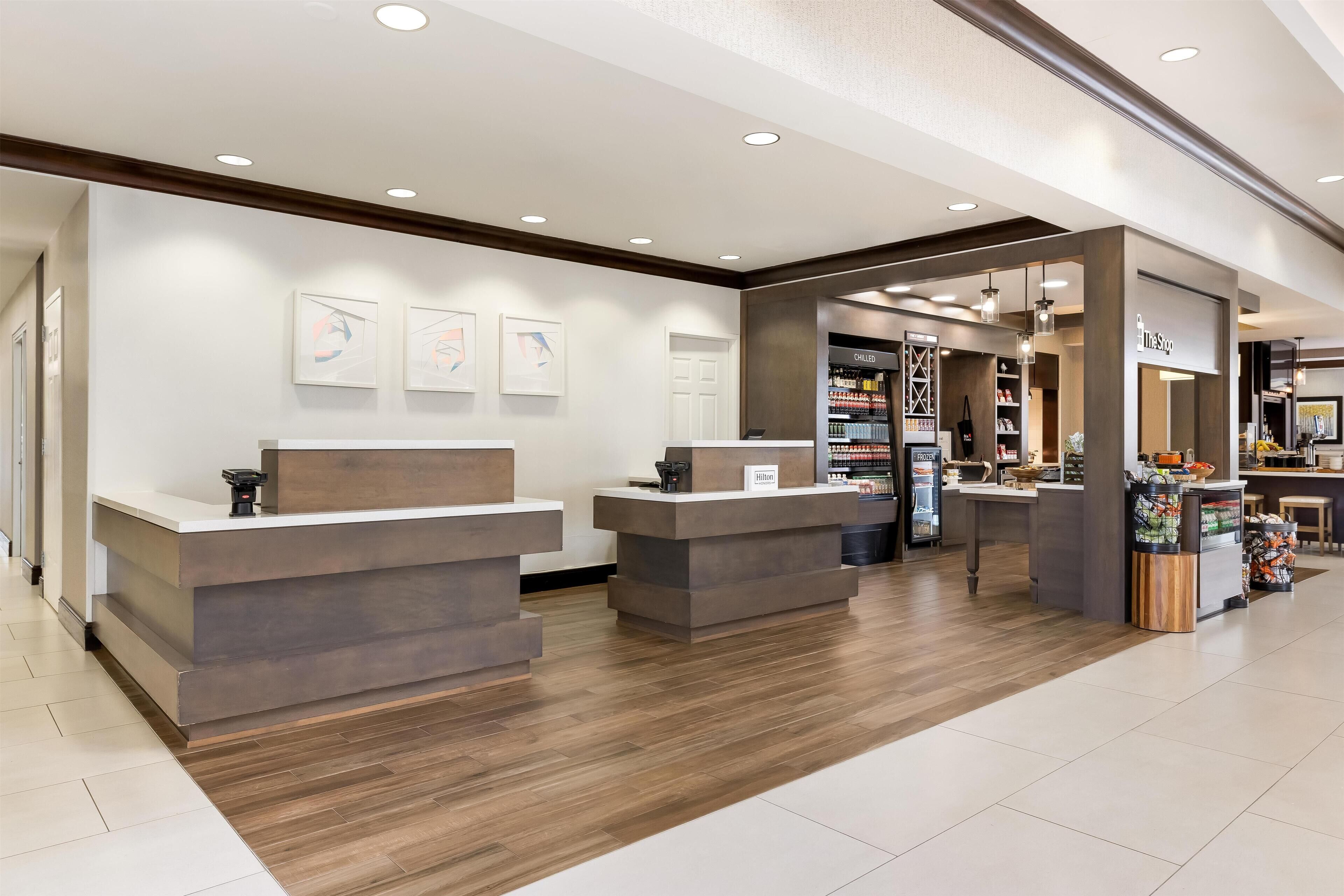 A hotel reception area with a modern design, featuring a reception desk, a seating area, and a display counter.