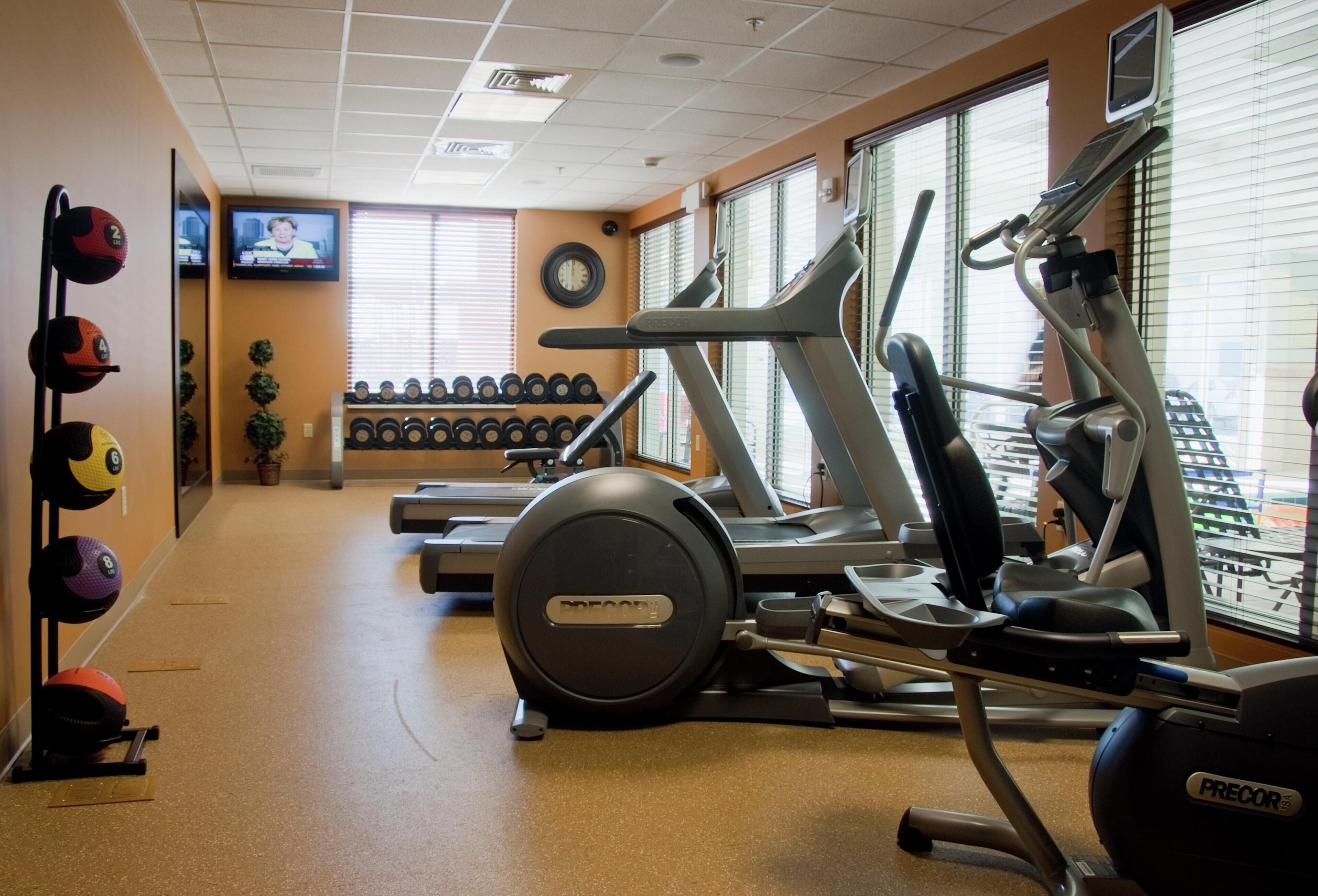A gym with treadmills, elliptical machines, and free weights.