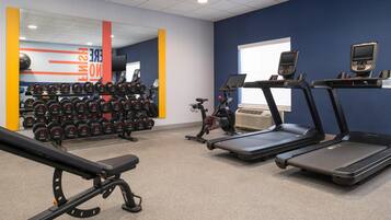 Une salle de sport équipée de tapis de course, d’haltères et d’un banc de musculation.