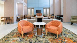 A spacious lobby with a central seating area, multiple tables, and a large wall-mounted screen. - Hampton Inn & Suites Prescott Valley (Prescott Valley)