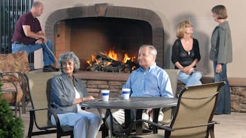A patio area with outdoor seating, a brick fireplace, and a small Christmas tree.