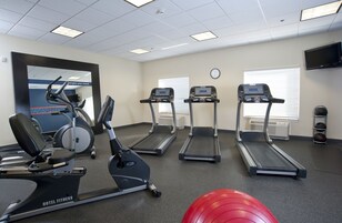 Un gimnasio de hotel con cintas de correr, una elíptica y una máquina de remo.