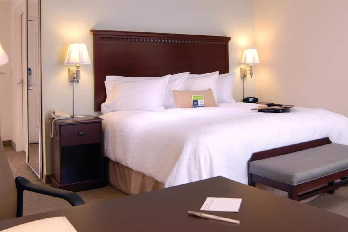 Ein Hotelzimmer mit einem großen Bett, Nachttischlampen, einem Nachttisch, einem Schreibtisch und einem Stuhl.