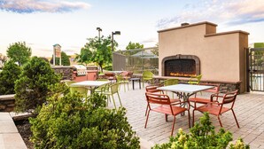 An outdoor patio with tables and chairs, a barbecue grill, and a fireplace. - Hampton Inn & Suites Prescott Valley (Prescott Valley)