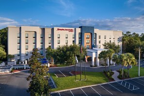 Un hotel Hampton Inn & Suites de diseño moderno, con estacionamiento y zonas verdes circundantes.
