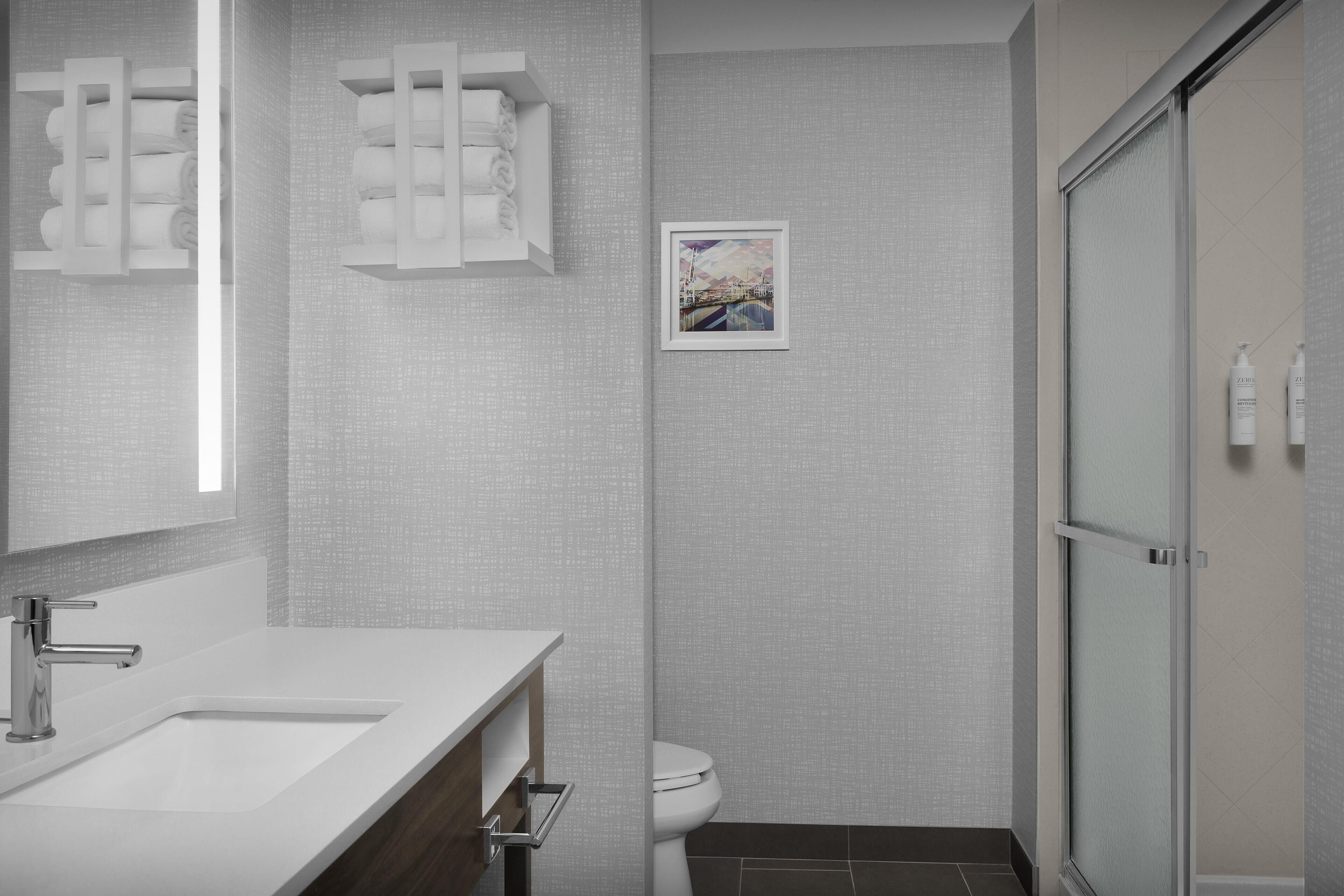 Un baño moderno con un espejo grande, un lavabo blanco y una zona de ducha.