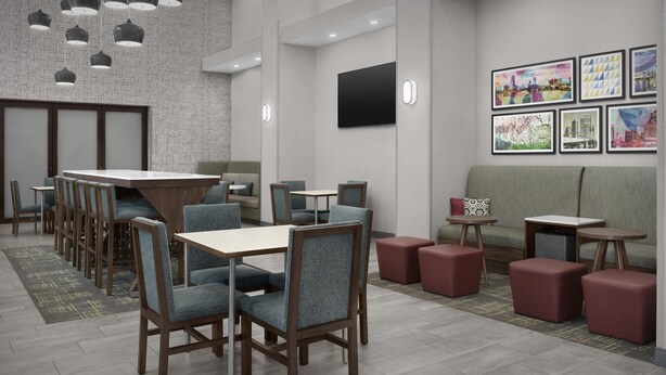 Un comedor moderno con una larga mesa y sillas, un sofá y pequeñas mesas con taburetes.